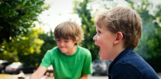 boy in blue shirt screaming near boy in green crew-neck shirt