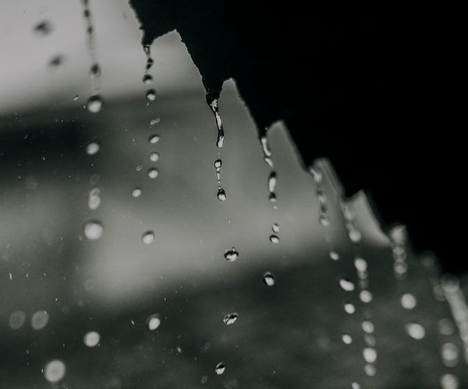 a black and white photo of rain drops on a window