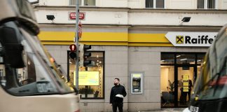 Raiffeisen Bank lansează „Adaugă bani”, noua funcționalitate din Smart Mobile care îți aduce toți banii într-un singur loc Man standing between two trams at a crosswalk.