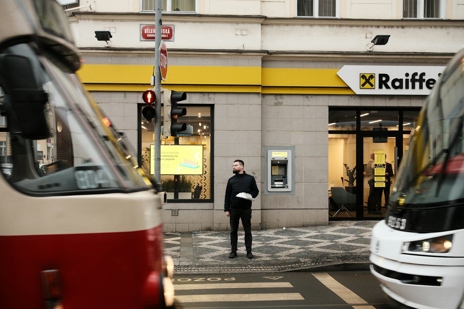Man standing between two trams at a crosswalk.