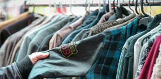 a person holding a shirt in front of a rack of shirts