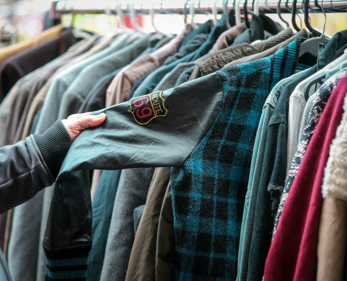 a person holding a shirt in front of a rack of shirts