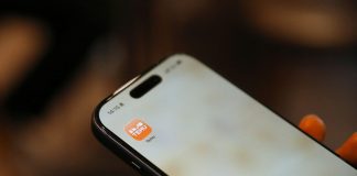 Person holding a smartphone with an app icon.