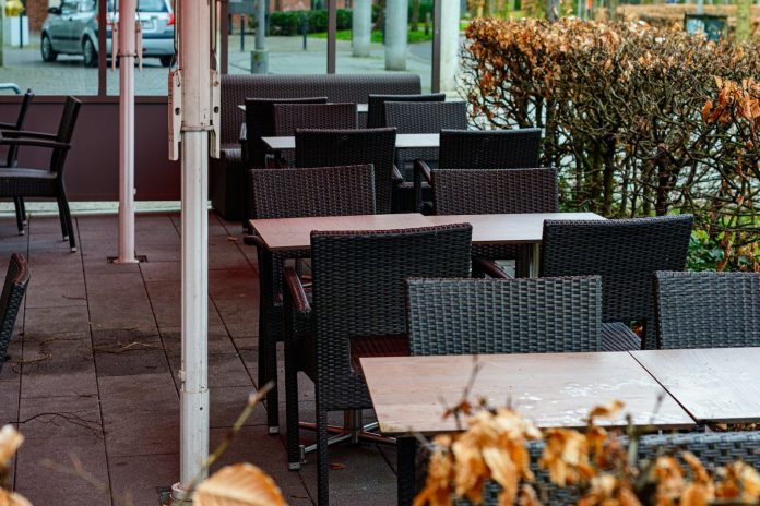 Empty outdoor cafe tables and chairs with dry leaves