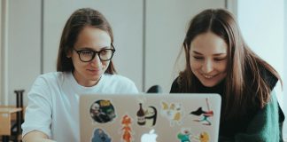 a couple of women sitting at a table with a laptop
