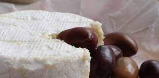 Cheese wheel with olives on parchment paper