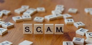Scam spelled with scrabbles on a wooden table